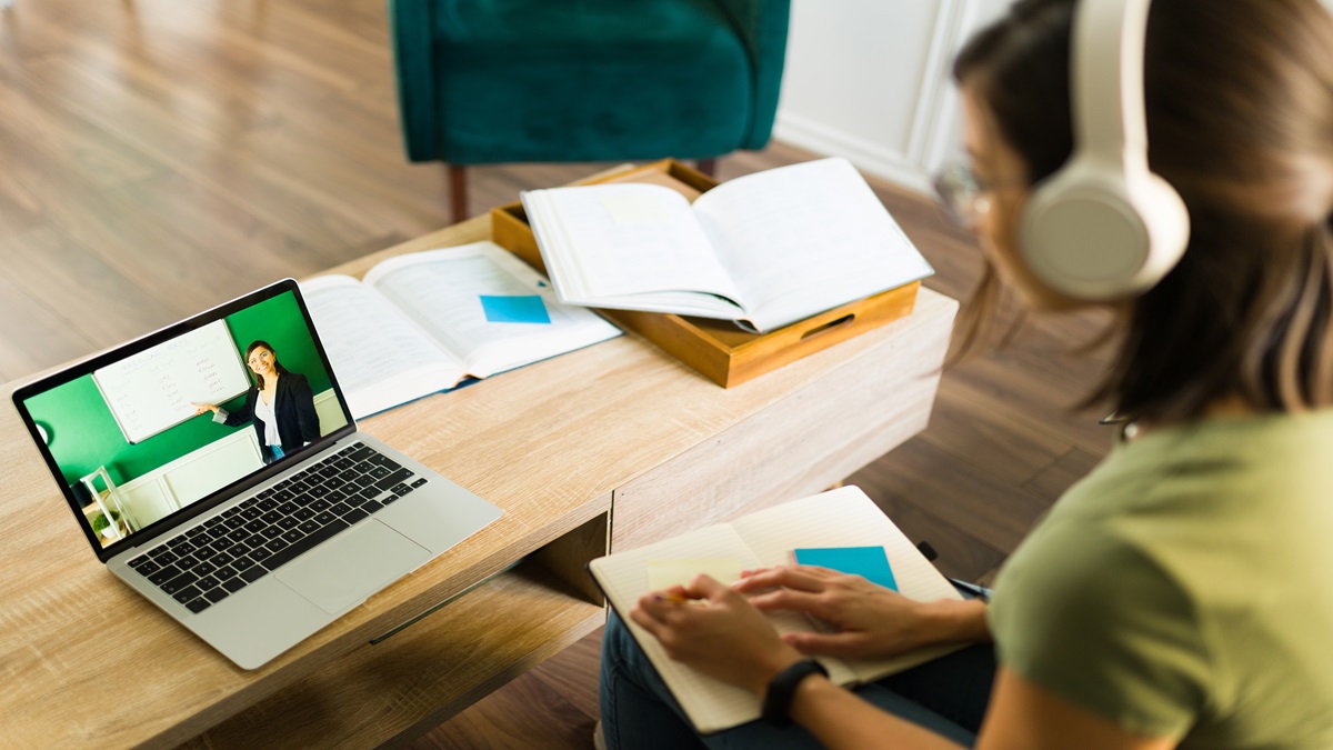 Pessoa estudando em casa com notebook e materiais didáticos em uma mesa organizada